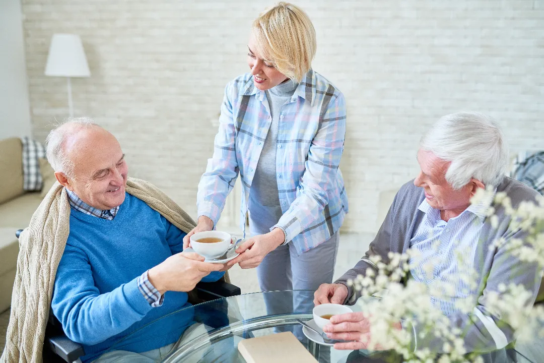 Woman serving tea to elderly visitors